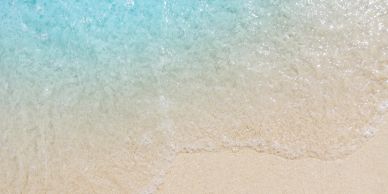 Clear sea water gently washing onto a sandy beach.