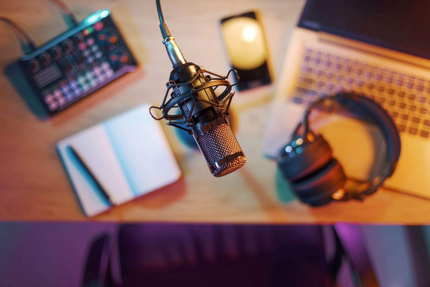 Close-up of a professional microphone with podcasting equipment on a desk.