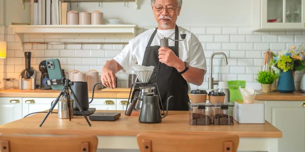 Elderly man brewing coffee with a hand grinder in a cozy kitchen.
