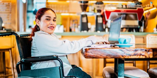 Latina wheelchair user in a cafe on her laptop