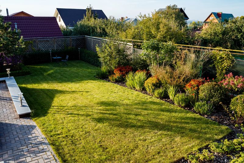 An aerial view showcasing a beautifully maintained, lush green lawn set in a backyard, surrounded by various plants and trees