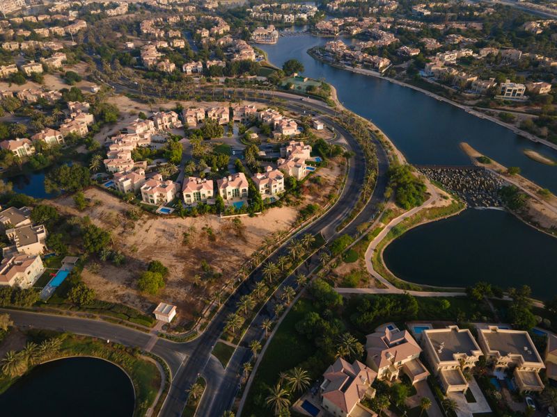 Aerial view of Jumeirah Islands, an exclusive neighborhood in Dubai, UAE, featuring luxury villas, shimmering man-made lakes, and lush greenery in a serene, upscale setting.
