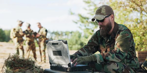 Soldier working on a laptop in the field.