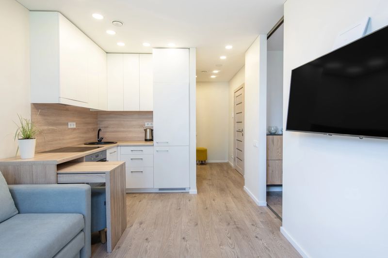 Stylish compact apartment with a contemporary kitchen, sleek furniture, wooden floor, and natural lighting. Perfectly arranged for modern city living, offering a cozy and functional space to relax.