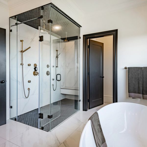 Modern bathroom with glass showers and black fixtures.
