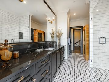 Modern bathroom with black countertops and white tiled walls.