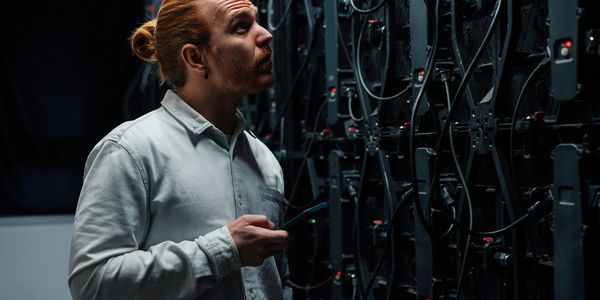 Technician checking server racks with a mobile device in a dark data center.