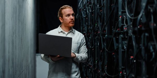 Technician working with a laptop in a server room.