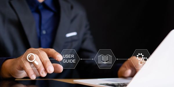 Person interacting with digital icons related to user guide and settings on a laptop.