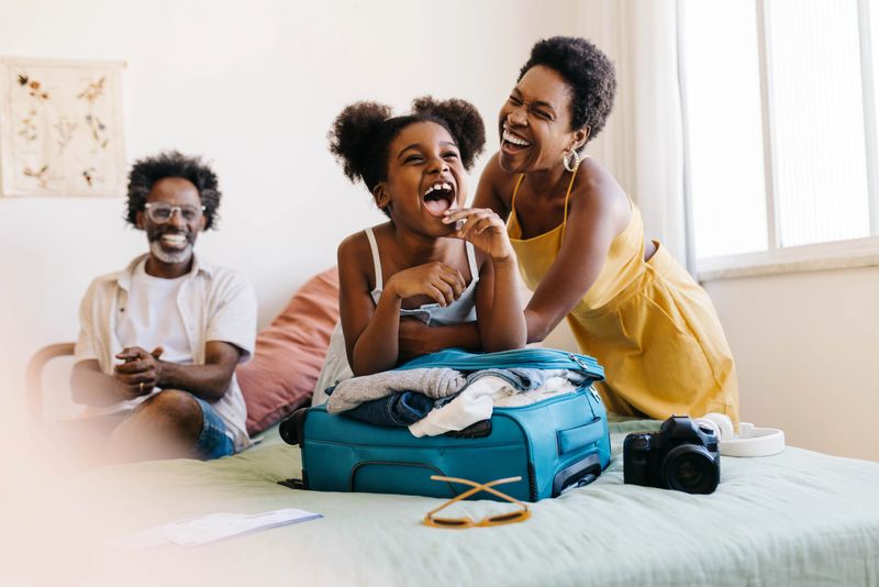 Happy family preparing for a vacation, laughing together as they pack travel essentials. Parents, along with their excited daughter, enjoy quality time planning and getting ready for a fun-filled holiday.