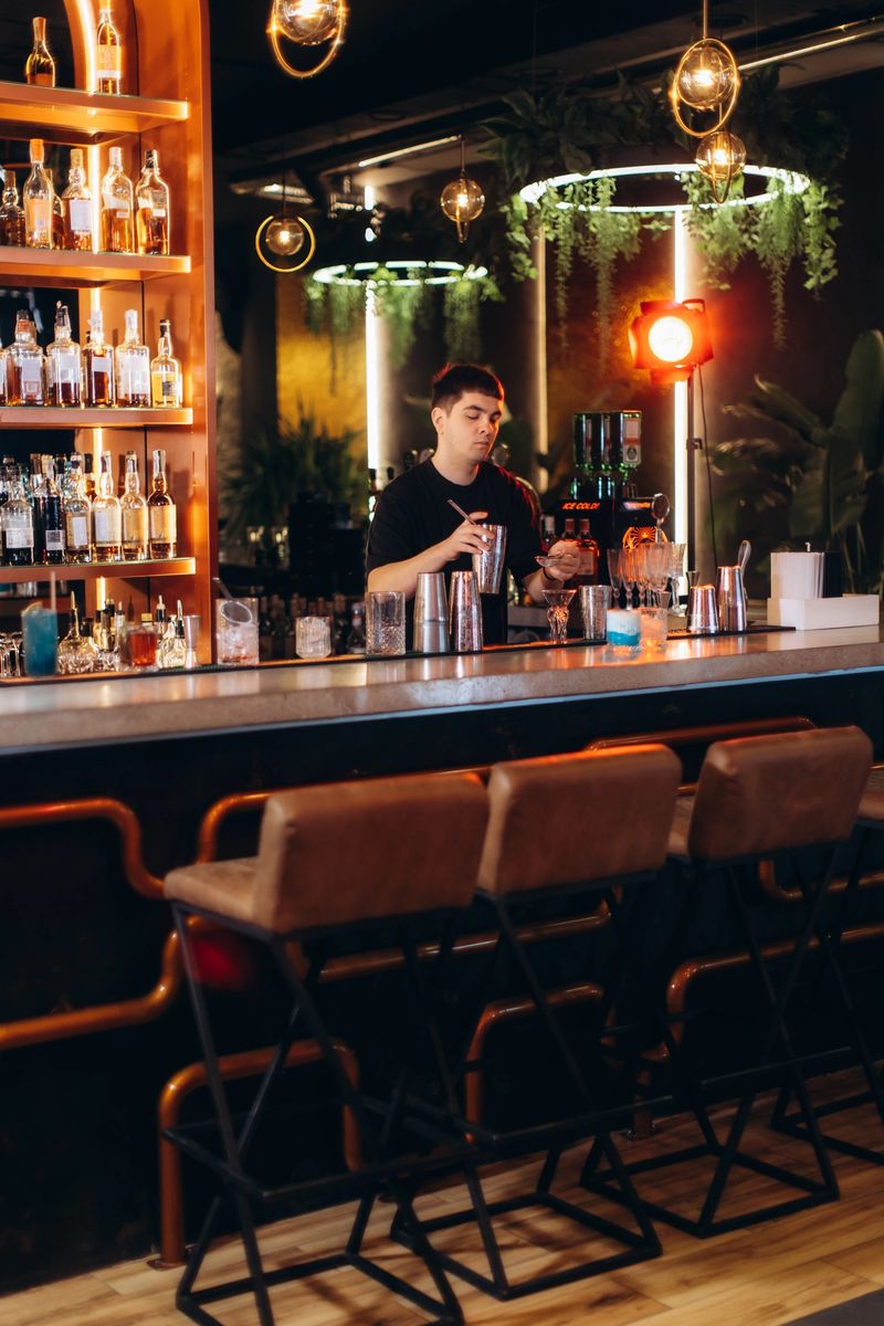Bartender working at a modern bar with stylish decor, preparing cocktails amidst a warm, inviting ambiance.