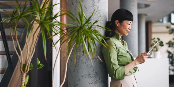 Woman leaning against a pillar while using her phone.