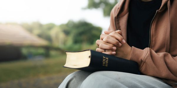 Person praying with a Bible.