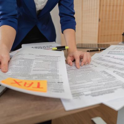 Person organizing tax documents on a desk.