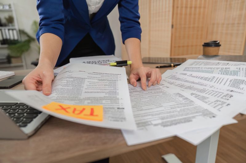 A professional woman is sorting through tax documents, highlighting her role in tax preparation and analysis in a contemporary office setting.