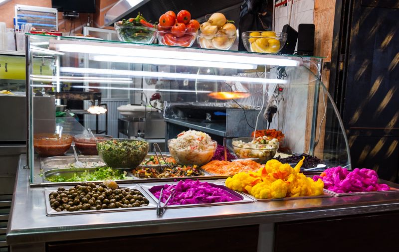 Assortment of fresh vegetable salads and colorful spicy pickles on the traditional food stand selling shawarma  sandwiches and other grilled meats in the Old City of Jerusalem, Israel.