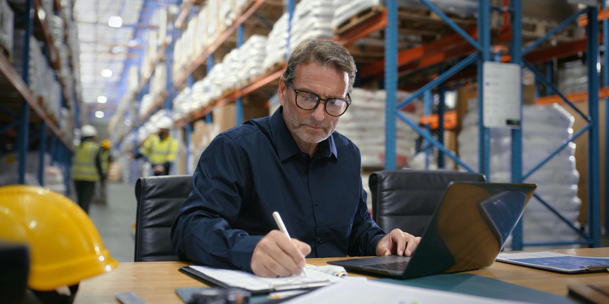 Man working at a desk in a warehouse environment.