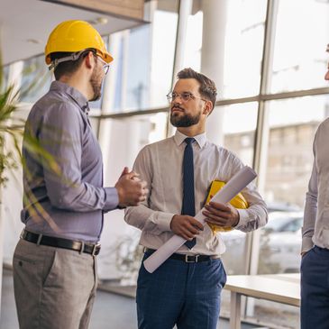 Engineers discussing a project in a modern office with blueprints.
