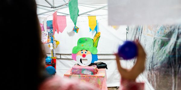 Person aiming a ball at a clown target in a carnival game.