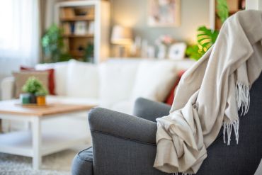 Cozy gray armchair with a soft blanket in a warmly lit living room.