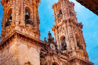 Torre de iglesia con arquitectura barroca bajo un cielo azul.