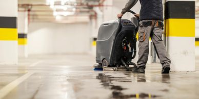 Worker cleaning floor in parking garage.