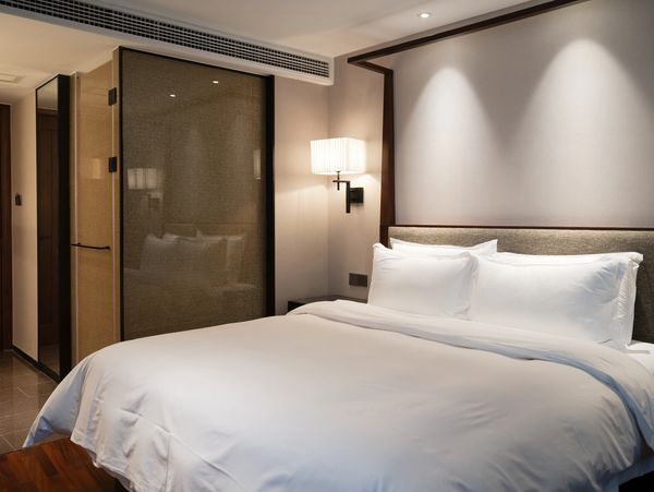 Minimalist hotel room with a large bed and soft lighting.