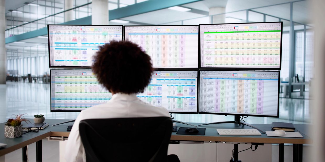 Medical billing specialist viewing multiple screens with data and revenue cycle reports. 