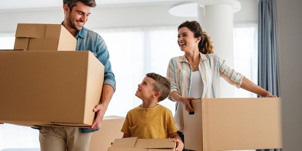 Happy family carrying boxes, moving into a new home.