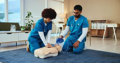 Two nurses performing CPR on a training mannequin.