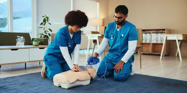 Two healthcare professionals practicing CPR on a medical mannequin.