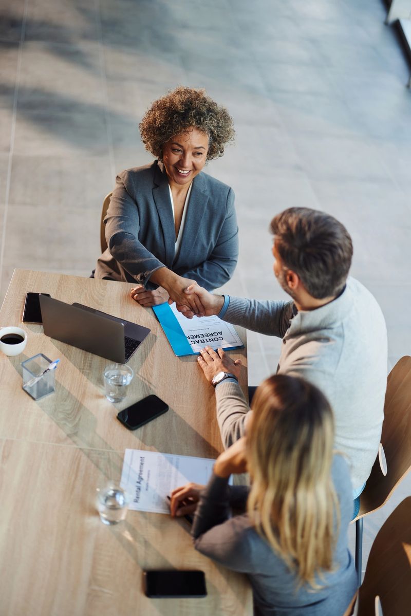 High angle view of happy female agent came to a successful agreement with a couple during a meeting in the office. Copy space.