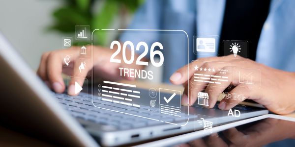 Person typing on a laptop with 2026 trends hologram overlay.