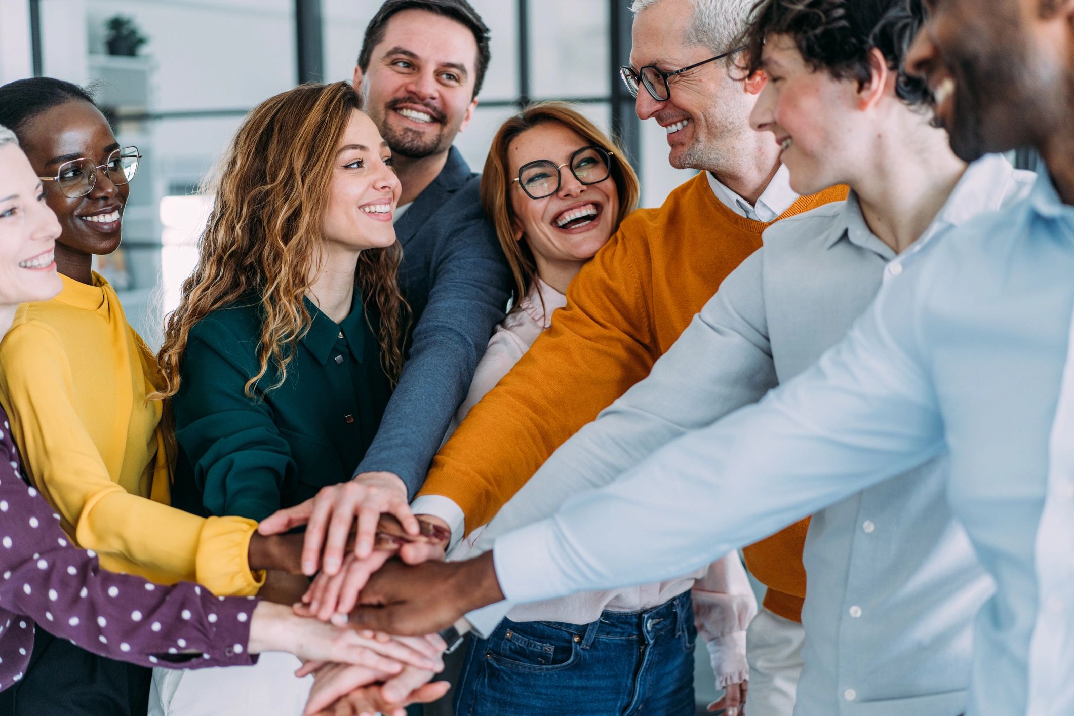 Happy diverse group celebrating teamwork with hands joined in unity.