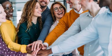 Group of diverse colleagues stacking hands in teamwork.