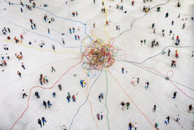 People connected by colorful yarn lines in a large open space.