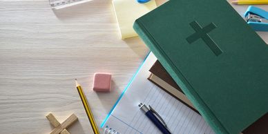 Bible, notebooks, and stationery on a wooden desk.