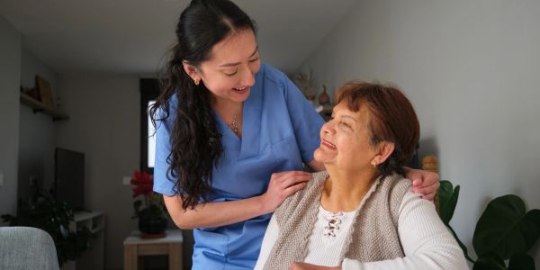 Caregiver comforting elderly woman with warm smile.