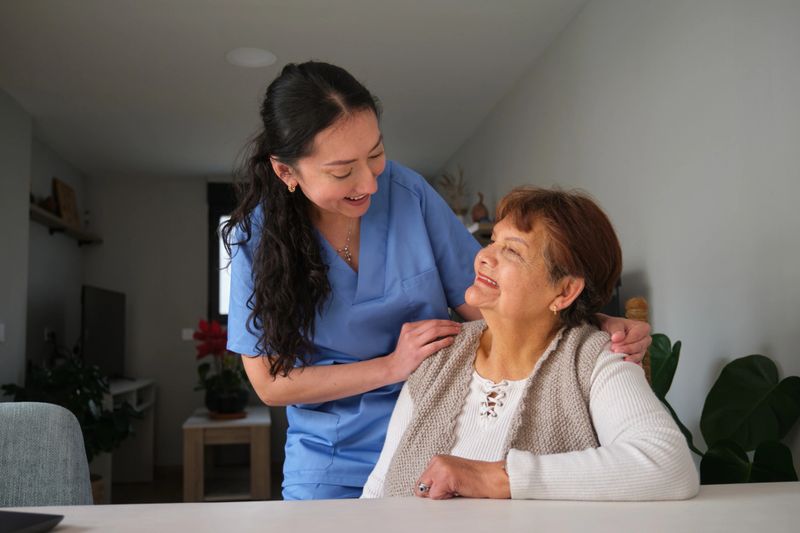 Young nurse is assisting and comforting a senior woman at home