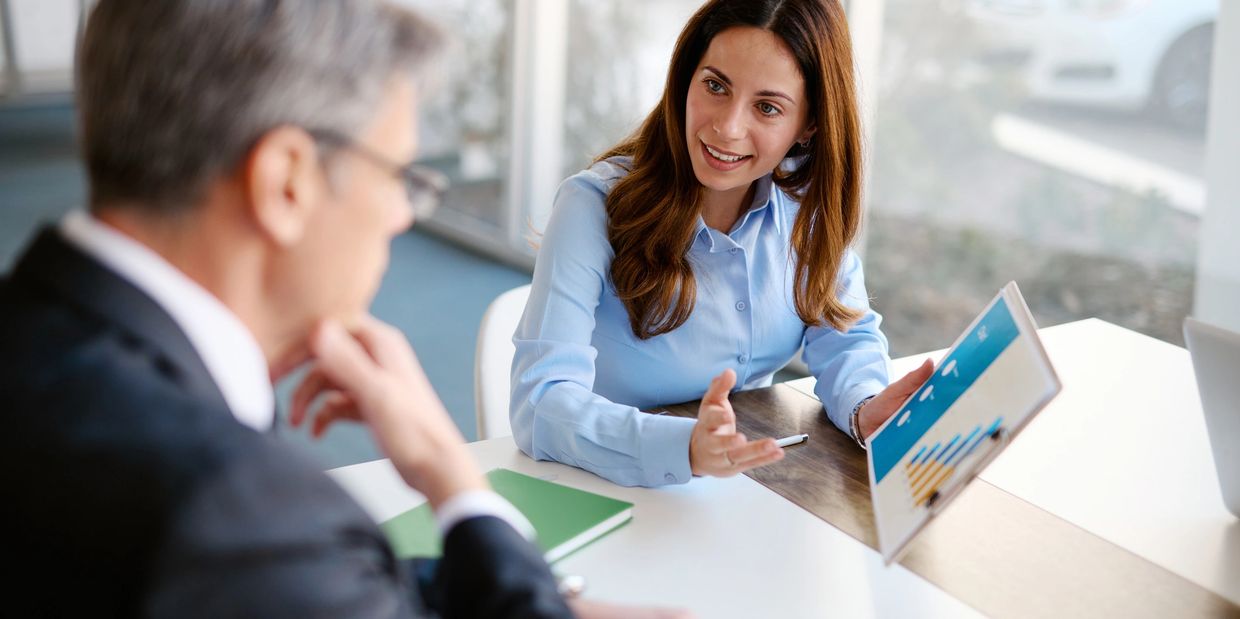 A woman presenting a chart to a man during a business meeting.