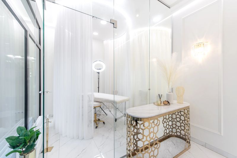 A chic beauty SPA clinic interior featuring gold accent furniture, white curtains, minimalist decor, creating a luxurious serene atmosphere ideal for professional treatment and personal care spaces.