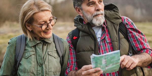 Mature couple outdoors consulting a map during a hike.