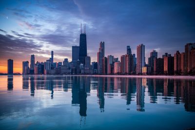 Chicago skyline at sunset with reflections on water.