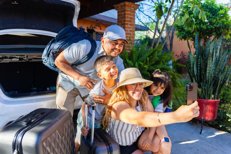 Latino family loading suitcases into the car for their road trip