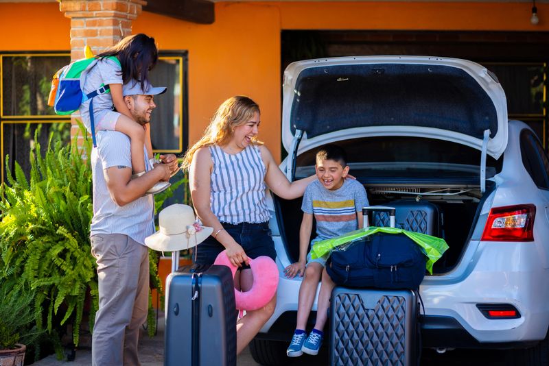 Latino family loading suitcases into the car for their road trip