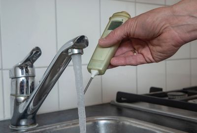 Testing water temperature with a digital thermometer.