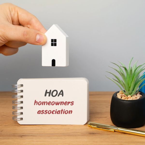 Hand holding a small white house over a card labeled HOA homeowners association.