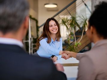 Smiling woman shaking hands during a business meeting.