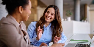 Two women happily talking at work.