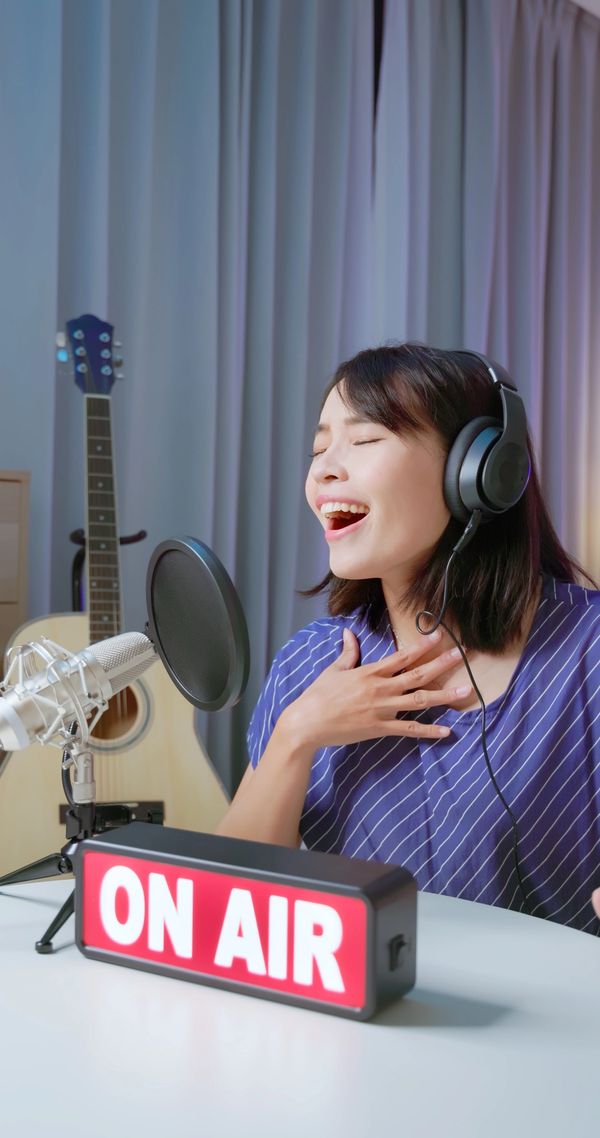 Woman singing passionately on air with headphones and microphone.